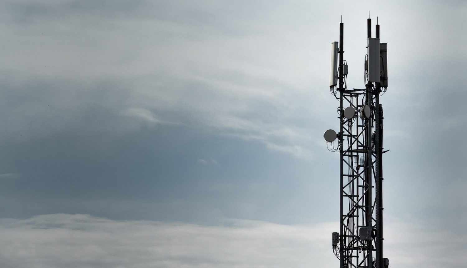Mobilo sakaru tornis uz mākoņainas debess fona