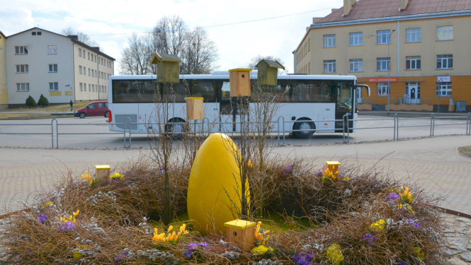 Lieldienu dekorācija - ola grozā priekšplānā un autobuss fonā