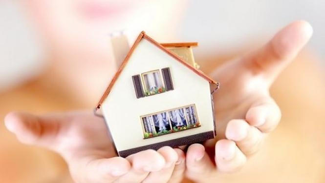 Miniatūra māja cilvēka rokās