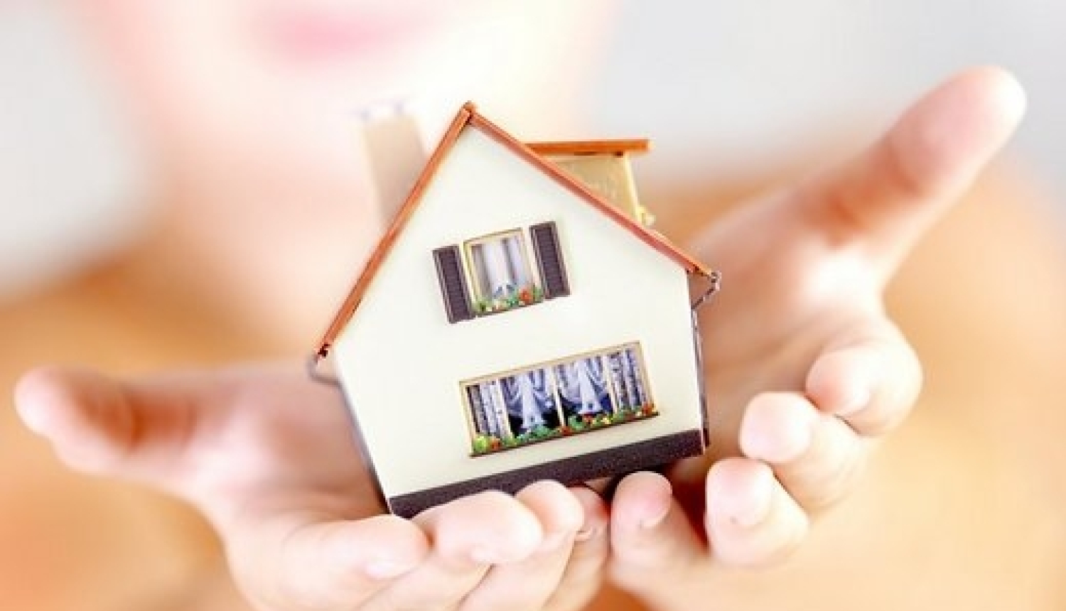 Miniatūra māja cilvēka rokās