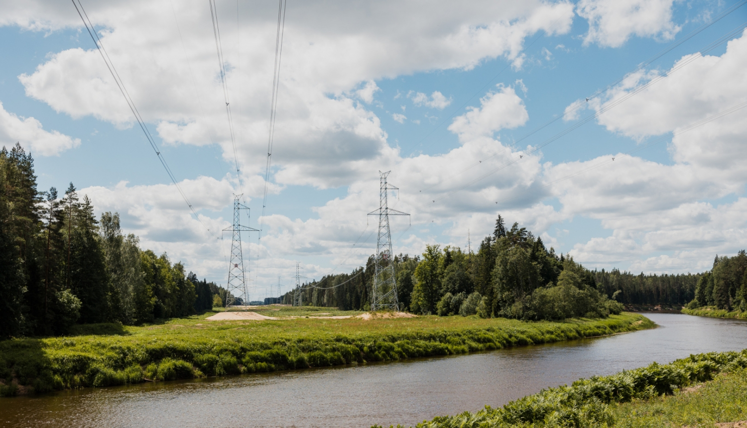 Upe ar augstsprieguma vadu torņiem fonā