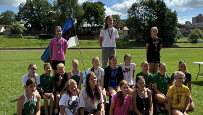 Bērni pie Latvijas un Igaunijas karogiem ārā uz zaļas zāles
