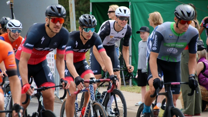 Velobraucēji sportisti krāsainos krekliņos uz riteņiem