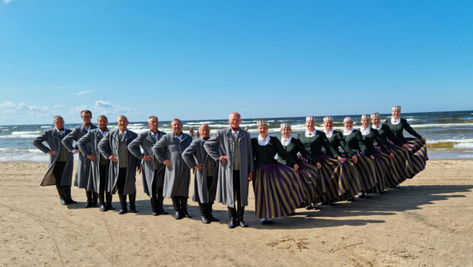 Deju kolektīvs tautas tērpos jūras piekrastē