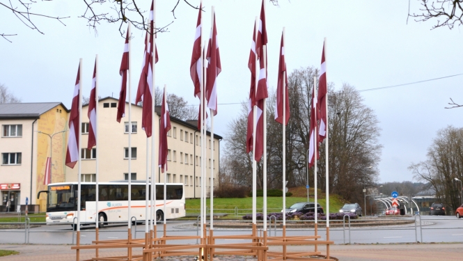 Latvijas karogu ornaments pie Valmieras apļa pilsētas centrā ar baltu autobusu fonā