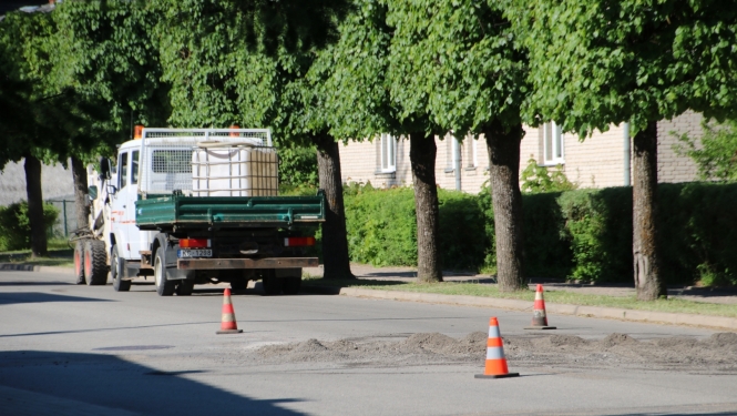 Ielas ceļš ar oranžajiem konusiņiem un remonstrādnieku busiņu