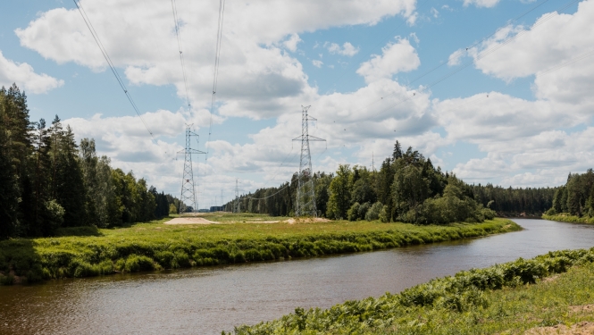 Upe ar augstsprieguma vadu torņiem fonā