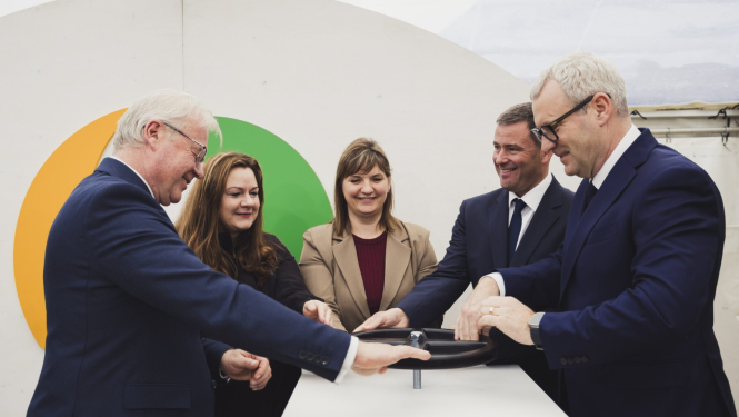 Vīrieši un sievietes uzvalkos pie simboliska vārsta