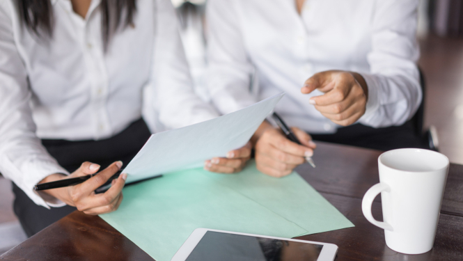 Divu kolēģu tuvplāns, kas strādā ar dokumentiem pie galda