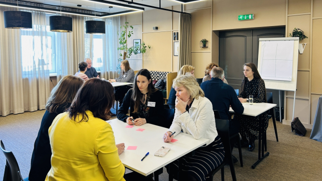 Cilvēki sēž pie apspriežu galdiem