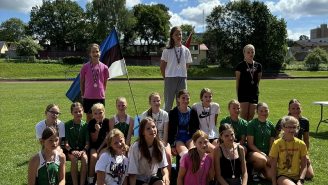 Bērni pie Latvijas un Igaunijas karogiem ārā uz zaļas zāles