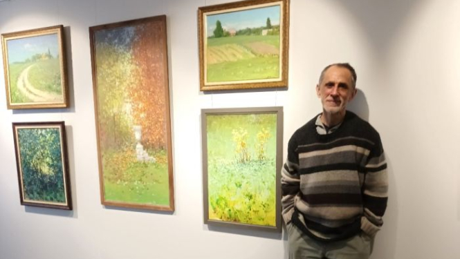 Vīrietis pie sienas ar gleznām