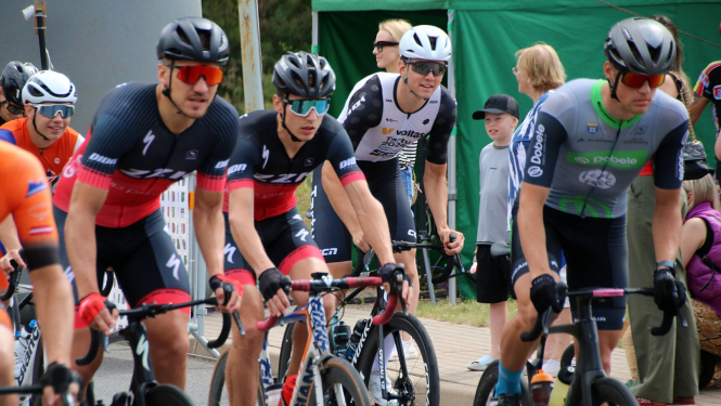 Velobraucēji sportisti krāsainos krekliņos uz riteņiem