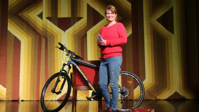 Smaidīga sieviete blakus laimētajam velosipēdam