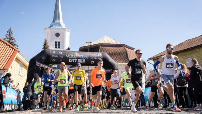 Skrējiena dalībnieki ar baznīcas torni fonā