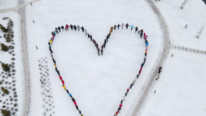 Drona foto no agšas ar cilvēkiem, kas sastājušies kopā veido sirds formu