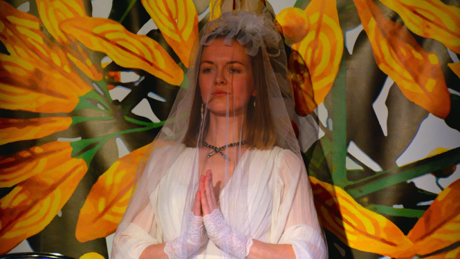 meitene tērpusies baltā ar plīvuru pie puķainas sienas 