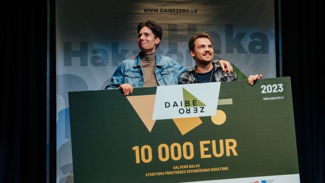 Smaidīgi vīrieši ar lielu baneri uz kā rakstīts 10 000 EUR