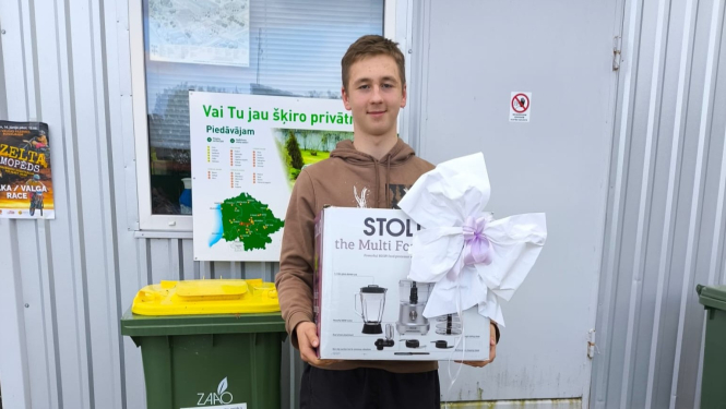 Smaidīgs jauns vīrietis, kurš rokās tur virtuves kombaina kasti