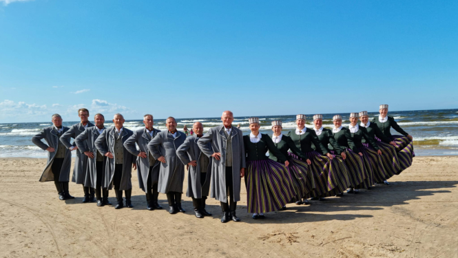 Deju kolektīvs tautas tērpos jūras piekrastē