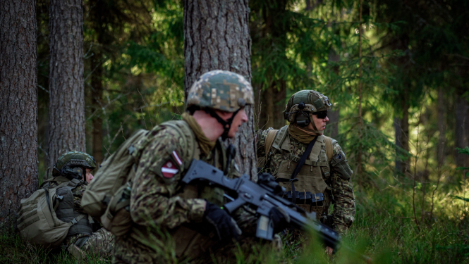 Karavīri kamuflāžas formas tērpos mežā