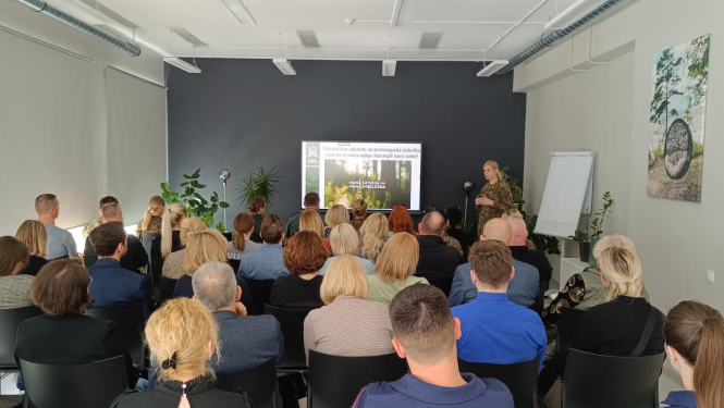 Speciālisti auditorijā klausās prezentāciju