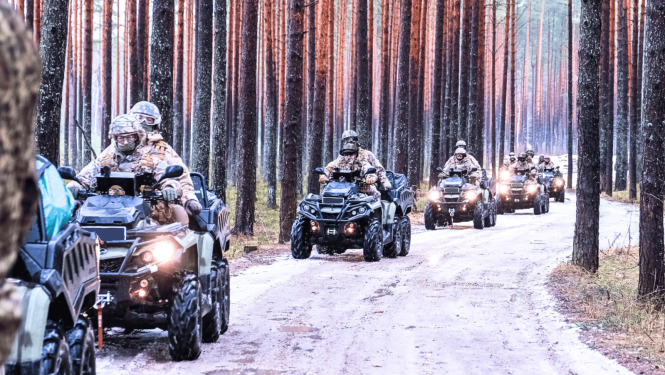 Zemessargi formas tērpos uz kvadracikliem uz ceļa mežā