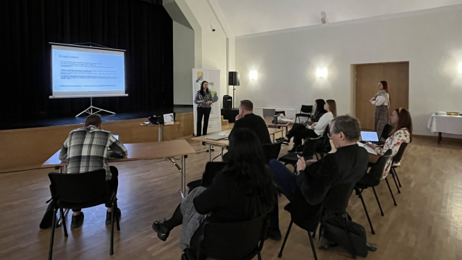 Zāle ar projektoru, ekrānu un 9 cilvēkiem