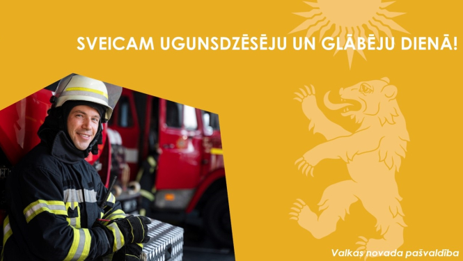 Dzeltens baneris ar Valkas novada ģērboņa lāci un smaidīga ugunsdzēsēja bilde