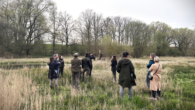 11 cilvēki stāv pļavā