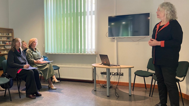 Cilvēki sēž krēslos un klausās ekspertā