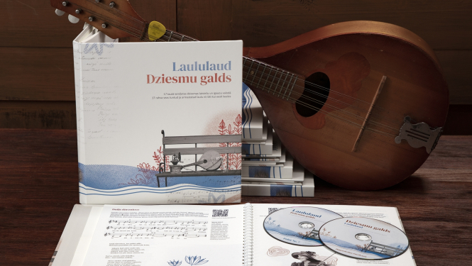 Uz galda uzlikta mandolīna ar "Dziesmu galds" grāmatu eksemplāriem