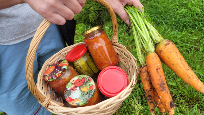 Cilvēka rokas tur burkānu un groziņu ar tomātu pastām