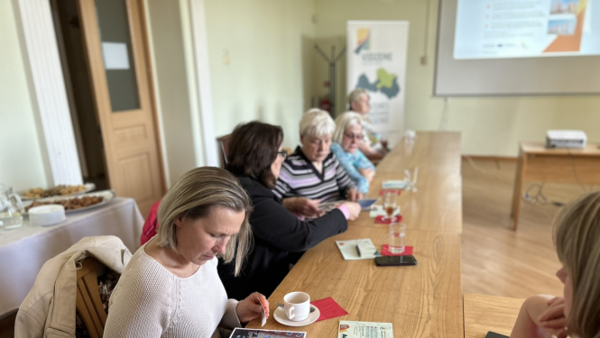 Sieviete pie galda skatās prezentācijas materiālos