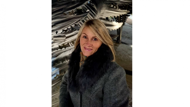 Mākslinieces portrets - sieviete ar gaišiem matiem pelēkā mētelī