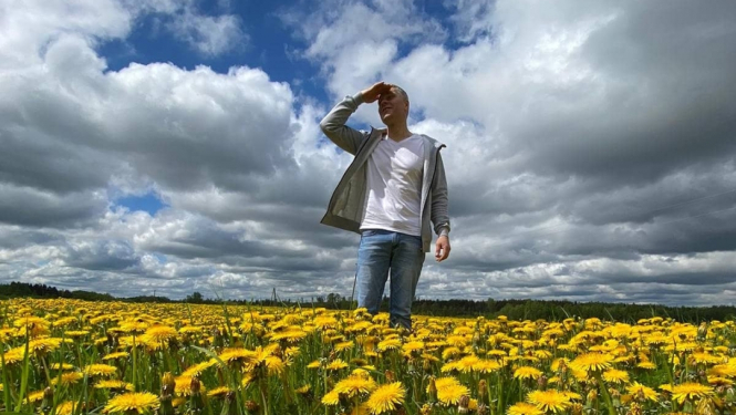 Vīrietis pieneņu laukā lūkojas tālumā