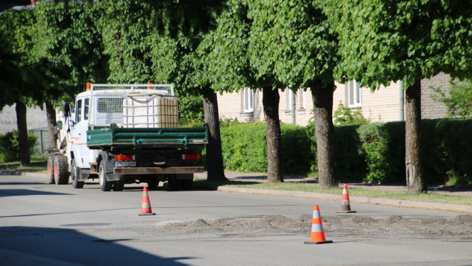 Ielas ceļš ar oranžajiem konusiņiem un remonstrādnieku busiņu