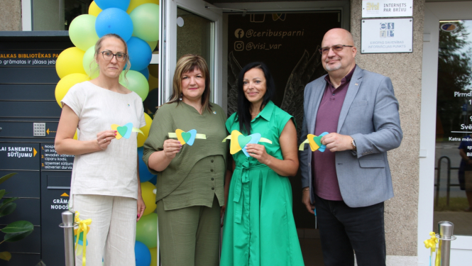 Četri cilvēki tur rokā svinīgas lentes daļas