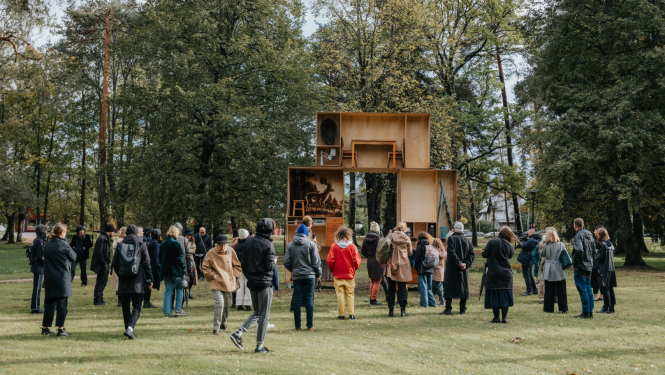 Cilvēku pūlis brīvdabā aplūko izstādi