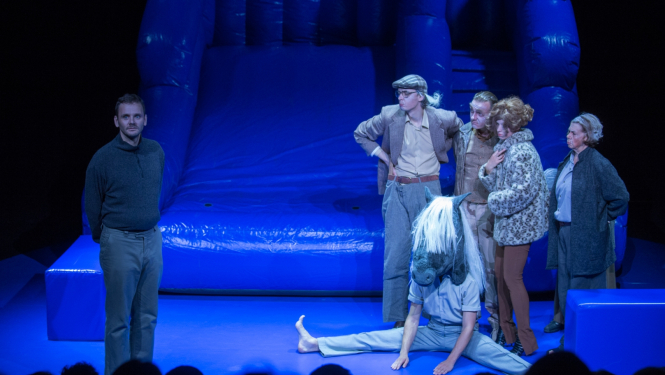 Skatuve zilā krāsā ar piepušamo atrakciju un aktieriem priekšplānā