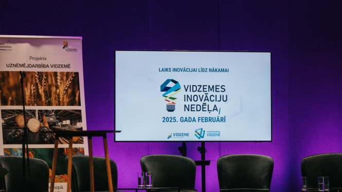 Konferences skatuve ar krēsliem un ekrānu ar Vidzemes Inovācijas nedēļas baneri