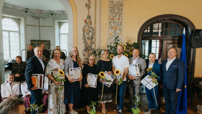 Cilvēkie svinīgā apģērbā pie Eiropas Savienības karoga