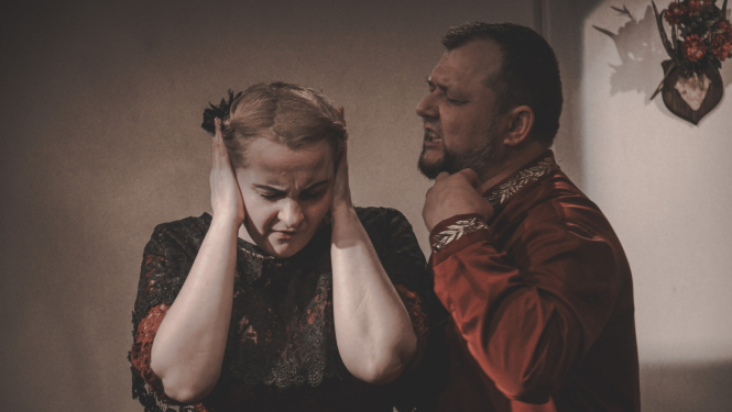 Vīrietis kliedz uz sievieti, kura pielikusi rokas uz ausīm