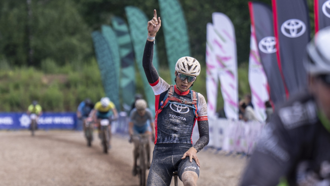 Velosipēdists dubļos ar paceltu roku 