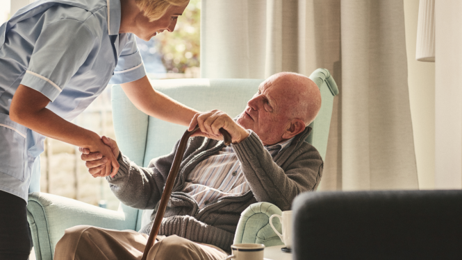 Vecs cilvēks ar spieķi sēž krēslā