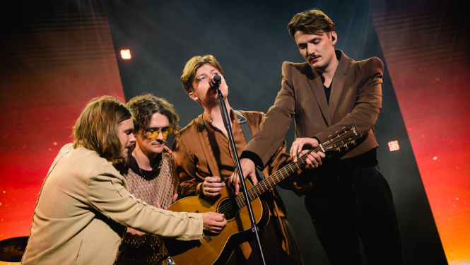 Sudden Lights grupa - 4 puiši uz skatuves pie mikrofona ar ģitāru