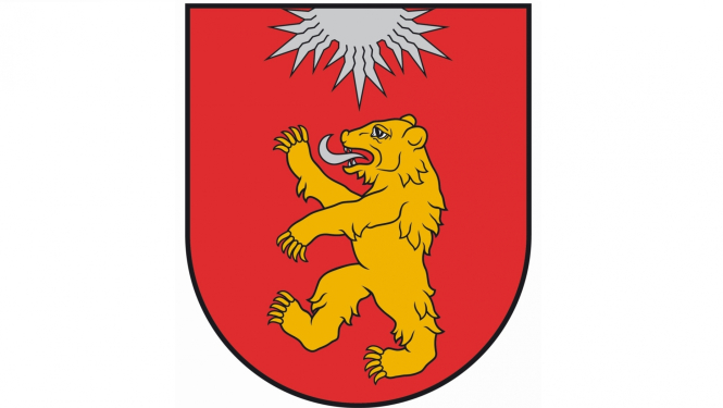 Valkas novada ģērbonis - Sarkanā laukā uzslējies zelta lācis ar sudraba mēli, no vairoga augšējās malas iznākoša sudraba saule ar trim lauzītu piecu staru kūļiem.