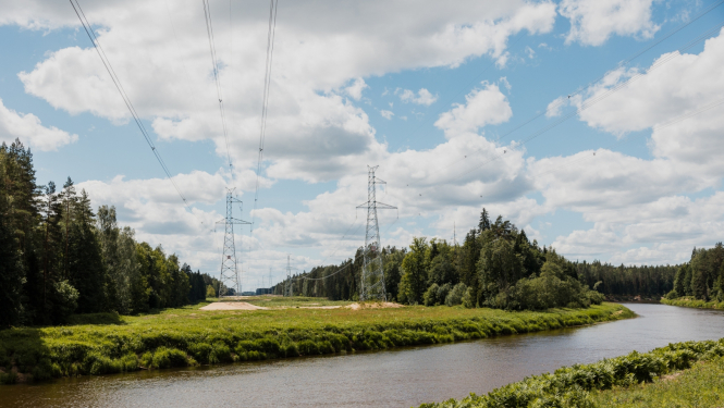 Upe ar augstsprieguma vadu torņiem fonā