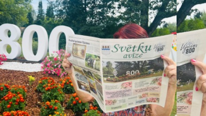 Sieviete lasa avīzi pie ziedu rotājuma ar skaitli 800