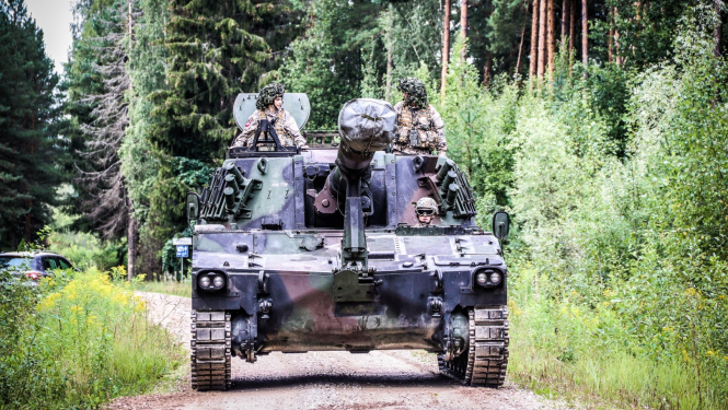 Bruņutransportieris uz grants ceļa mežā